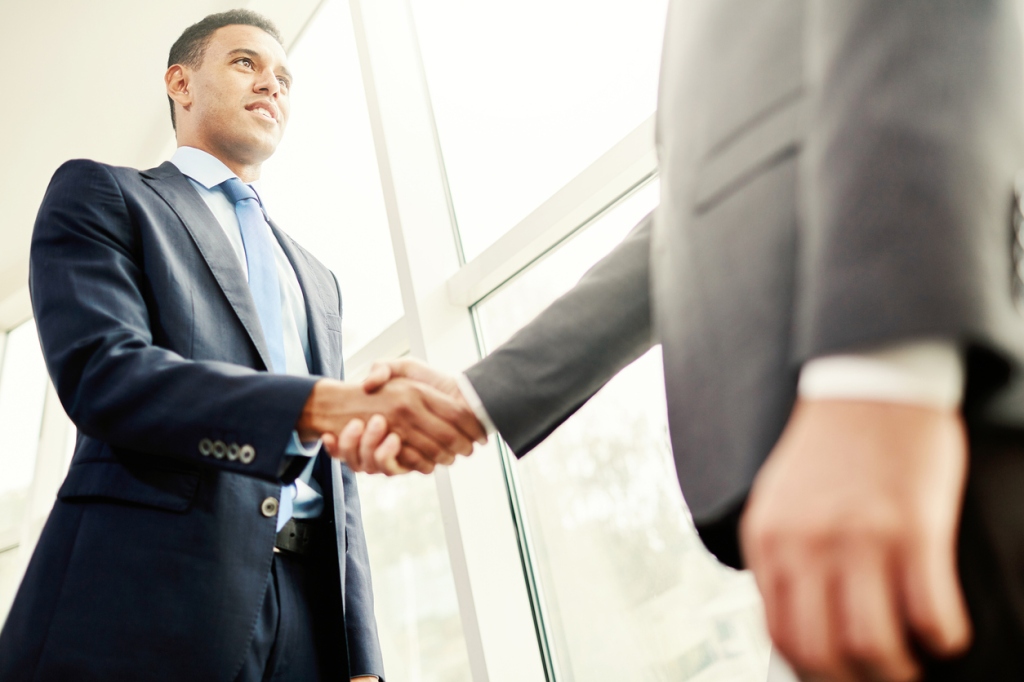 Male executives handshaking in an office building.
